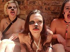 Three naked women engage in kinky tongue play outdoors